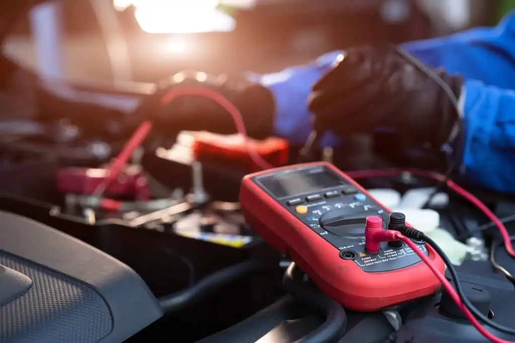 Asian technician measure voltage of battery in the car at service station, Maintenance and repair