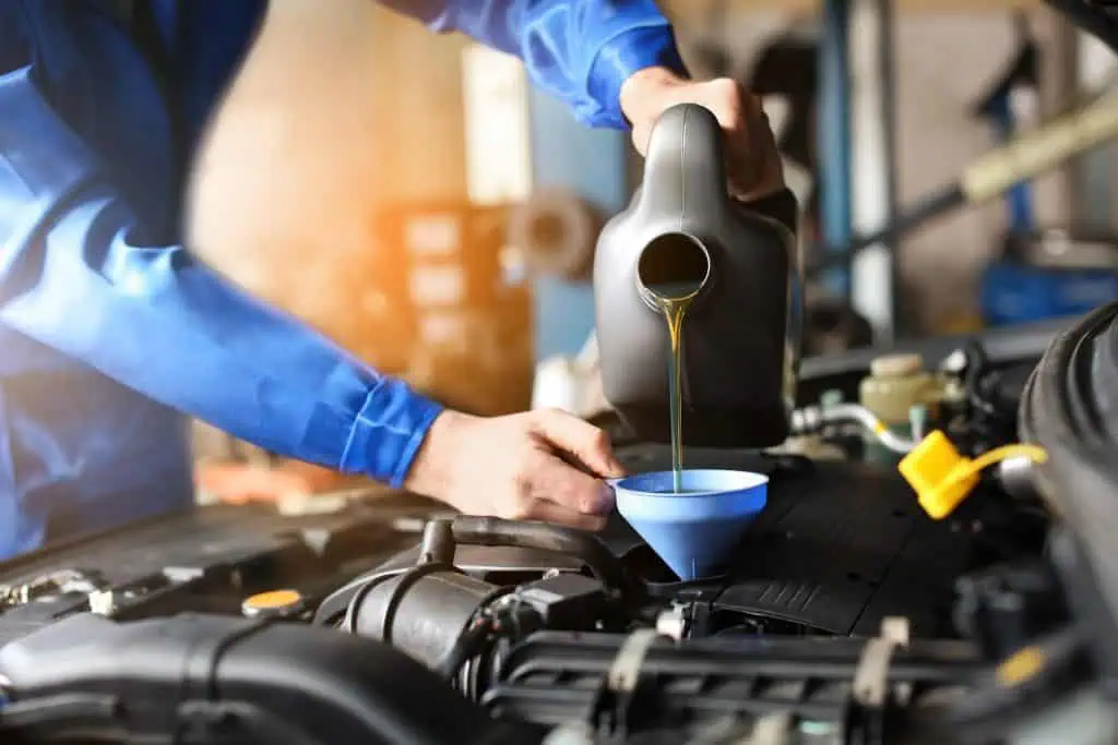 Male mechanic refilling car oil in service center